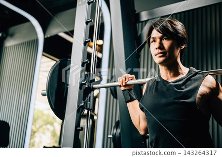 Asian muscular man guy performing a squat exercise legs heavy weights with a barbell in gym interior, male doing lifting barbell work out at fitness gym, sport workout healthy lifestyle Asian muscular man guy performing a squat exercise legs heavy weights with a barbell in gym interior, male doing lifting barbell work out at fitness gym, sport workout healthy lifestyle 143264317