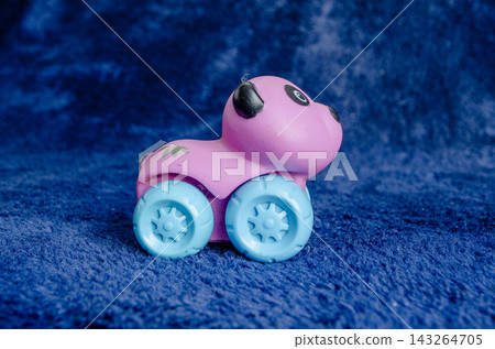 Bright pink toy car with blue wheels on a blue background Bright pink toy car with blue wheels on a blue background 143264705