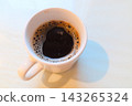 一杯盛在白色杯子裡的熱咖啡，一張寬敞的桌子。 143265324