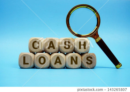 Cash Loans alphabet letters wooden cube and magnifying glass on blue background Cash Loans alphabet letters wooden cube and magnifying glass on blue background 143265807