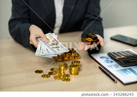 Businessman Holding US Dollar Bills and Gold Bars Comparing Investment Options at Office Desk Businessman Holding US Dollar Bills and Gold Bars Comparing Investment Options at Office Desk 143266243