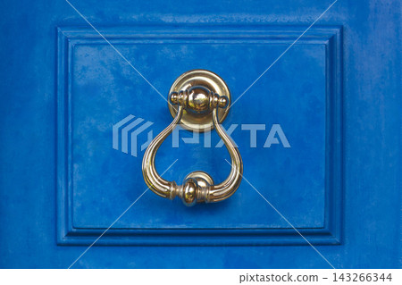 Vintage brass door knocker on a vibrant blue wooden door in Bodrum 143266344