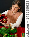 Woman Decorating Christmas Tree with Red Baubles 143266638