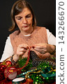 Mature Woman Decorating a Christmas Wreath 143266670