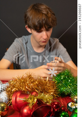Young Man Making a Snowflake Christmas Ornament 143266687