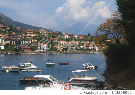Motorboats moored in a calm blue bay with a coastal village on Lake Como in Italy Motorboats moored in a calm blue bay with a coastal village on Lake Como in Italy 143266992