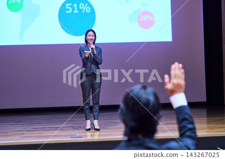 A female presenter responding to a participant who raised their hand at the presentation venue. A female presenter responding to a participant who raised their hand at the presentation venue. 143267025