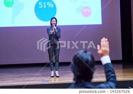 A female presenter responding to a participant who raised their hand at the presentation venue. A female presenter responding to a participant who raised their hand at the presentation venue. 143267026