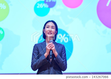 一位女商人正在用麥克風做演講,她身後有一個螢幕。 一位女商人正在用麥克風做演講,她身後有一個螢幕。 143267066