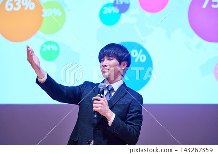 A young business person giving a presentation at a seminar, using data to support their presentation. 143267359