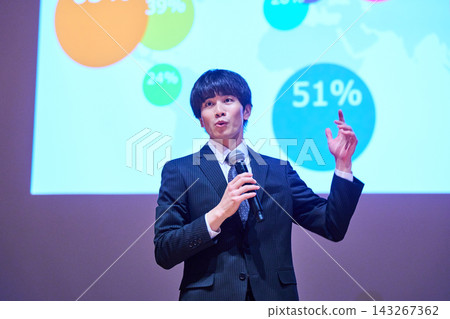 A young business person giving a presentation at a seminar, using data to support their presentation. 143267362
