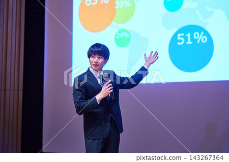 A young business person giving a presentation at a seminar, using data to support their presentation. A young business person giving a presentation at a seminar, using data to support their presentation. 143267364