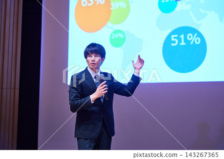 A young business person giving a presentation at a seminar, using data to support their presentation. A young business person giving a presentation at a seminar, using data to support their presentation. 143267365