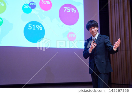 A young business person giving a presentation at a seminar, using data to support their presentation. 143267366