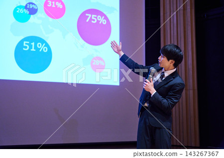 A young business person giving a presentation at a seminar, using data to support their presentation. 143267367