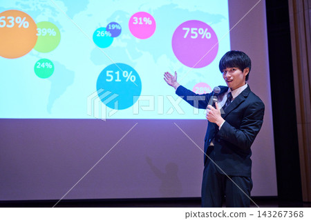 A young business person giving a presentation at a seminar, using data to support their presentation. A young business person giving a presentation at a seminar, using data to support their presentation. 143267368
