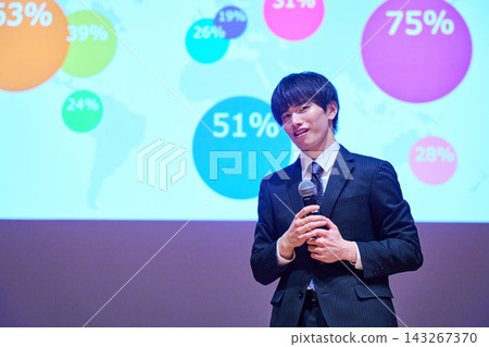 A young business person giving a presentation at a seminar, using data to support their presentation. A young business person giving a presentation at a seminar, using data to support their presentation. 143267370