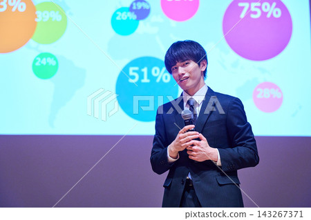 A young business person giving a presentation at a seminar, using data to support their presentation. A young business person giving a presentation at a seminar, using data to support their presentation. 143267371