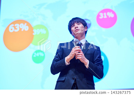 A young business person giving a presentation at a seminar, using data to support their presentation. A young business person giving a presentation at a seminar, using data to support their presentation. 143267375