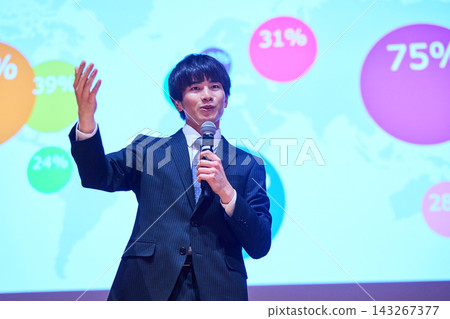 A young business person giving a presentation at a seminar, using data to support their presentation. A young business person giving a presentation at a seminar, using data to support their presentation. 143267377
