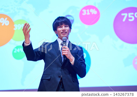 A young business person giving a presentation at a seminar, using data to support their presentation. 143267378