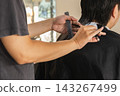 Close up of a professional hairdresser using scissors to trim client hair in salon. 143267499