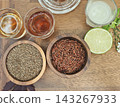 Top view of healthy herbal tea ingredients with roasted rice, seeds, fresh lime, and tea shots on a wooden table. 143267933