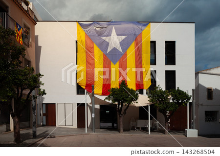 Large Estelada banner on building facade in Catalonia Spain symbolizing Catalan independence movement and regional identity. Editorial image for politics culture and activism Large Estelada banner on building facade in Catalonia Spain symbolizing Catalan independence movement and regional identity. Editorial image for politics culture and activism 143268504
