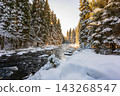 Winter view of the Vydra River flowing through the Modrava valley in Sumava National Park, Czech Republic, with warm sunrise light illuminating the snowy forest and landscape. 143268547