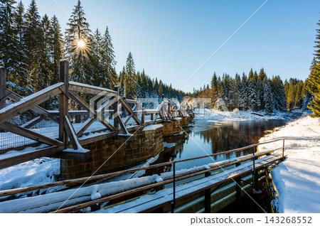Timber Rafting Bridge (Rechle) near Modrava in Sumava National Park, Czech Republic, covered in snow and illuminated by sunset, connected to the historic Vchynice-Tetov rafting canal. Timber Rafting Bridge (Rechle) near Modrava in Sumava National Park, Czech Republic, covered in snow and illuminated by sunset, connected to the historic Vchynice-Tetov rafting canal. 143268552