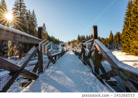 Timber Rafting Bridge (Rechle) near Modrava in Sumava National Park, Czech Republic, covered in snow and illuminated by sunset, connected to the historic Vchynice-Tetov rafting canal. Timber Rafting Bridge (Rechle) near Modrava in Sumava National Park, Czech Republic, covered in snow and illuminated by sunset, connected to the historic Vchynice-Tetov rafting canal. 143268553
