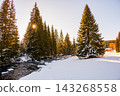 Winter view of the Vydra River flowing through the Modrava valley in Sumava National Park, Czech Republic, with warm sunrise light illuminating the snowy forest and landscape. 143268558