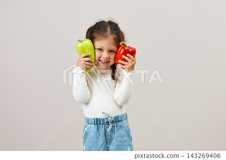 Happy little girl enjoying bell peppers, showing healthy eating habits and good nutrition with fresh vegetables Happy little girl enjoying bell peppers, showing healthy eating habits and good nutrition with fresh vegetables 143269406