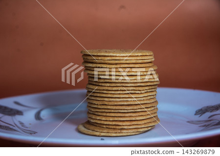 Tall Stack of Round Golden Biscuits Placed on a White Ceramic Plate Featuring Warm Lighting Tall Stack of Round Golden Biscuits Placed on a White Ceramic Plate Featuring Warm Lighting 143269879