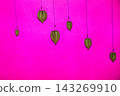 Dried Physalis Husks Hanging on Thin Strings Against a Vibrant Neon Pink Background for Art Design 143269910