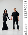 Couple celebrates pregnancy with joyful studio portrait 143270043