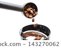 Coffee beans fall into a grinder from a measuring scoop 143270062