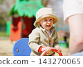 Laughing Toddler Playing on a Seesaw at an Outdoor Park 143270065