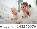 Loving mother looking adoringly at her cute baby on bed 143270079