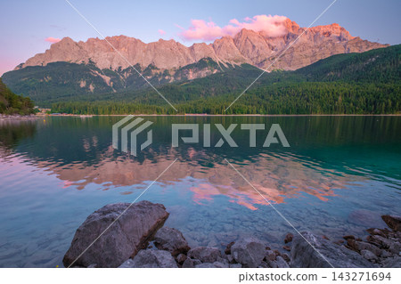 Peaceful blue hour twilight scene at Eibsee lake with the Zugspitze mountain peaks reflected in the still water in Berchtesgaden, Germany. Peaceful blue hour twilight scene at Eibsee lake with the Zugspitze mountain peaks reflected in the still water in Berchtesgaden, Germany. 143271694