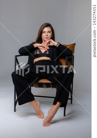 Young businesswoman posing barefoot sitting on a modern chair 143274351