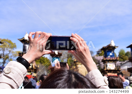 Inuyama City, Aichi Prefecture, Japan: Springtime Inuyama Festival and cherry blossoms in full bloom; floats gathered in front of Inuyama Castle Square; tourists taking photos with their smartphones. Inuyama City, Aichi Prefecture, Japan: Springtime Inuyama Festival and cherry blossoms in full bloom; floats gathered in front of Inuyama Castle Square; tourists taking photos with their smartphones. 143274499