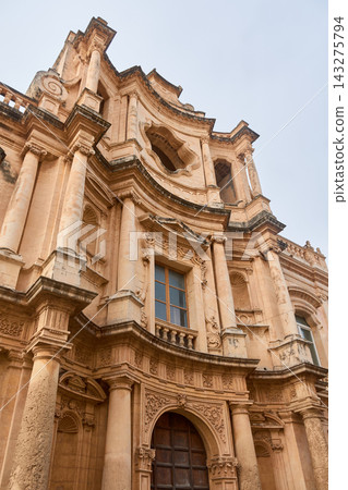 The beautiful Baroque architecture of the facade of the Church of San Carlo in Noto, Sicily, stands out. The beautiful Baroque architecture of the facade of the Church of San Carlo in Noto, Sicily, stands out. 143275794