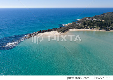 An aerial view of Laggers Point surrounded by clear turquoise ocean, with the historic Trial Bay Gaol visible in the background. This coastal landmark lies within Arakoon National Park An aerial view of Laggers Point surrounded by clear turquoise ocean, with the historic Trial Bay Gaol visible in the background. This coastal landmark lies within Arakoon National Park 143275988
