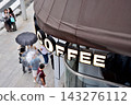 People walking under a coffee shop sign in Ginza 3-chome 143276112