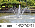 A man resting behind a fountain in a park during a heatwave. 143276251