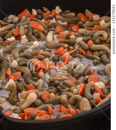 Overhead view of pickled small gherkins and sliced carrots in vegetable brine marinade Overhead view of pickled small gherkins and sliced carrots in vegetable brine marinade 143278041