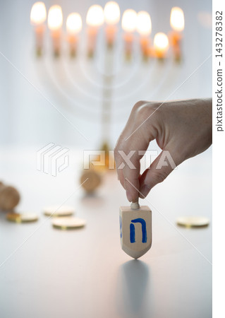 Hand holding a wooden dreidel on a bright Hanukkah tabletop scene Hand holding a wooden dreidel on a bright Hanukkah tabletop scene 143278382