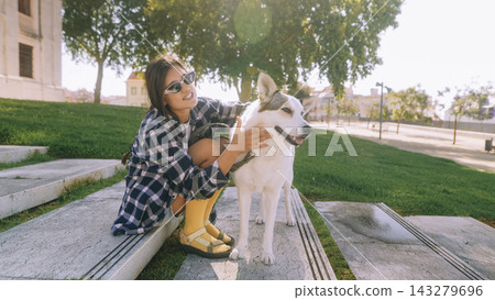 Woman petting dog on sunny steps in a park Woman petting dog on sunny steps in a park 143279696