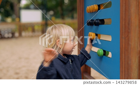 White blond toddler exploring sensory wall at playground 143279858